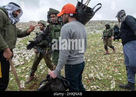 L'ufficiale dell'IDF negozia con gli attivisti sopra il punto di piantagione. Centinaia di attivisti di pace israeliani e palestinesi avevano piantato ulivi nel villaggio palestinese di Burin, sotto l'avamposto illegale ebraico di Givát Ronen. Due settimane prima dell'evento, un gruppo di attivisti di pace ebrei arrivati per la piantagione di olive sono stati violentemente attaccati dai giovani di Givát Ronen. Oggi, le forze dell'IDF si erano separate tra gli attivisti e i coloni. Un attivista israeliano è stato arrestato durante l'evento. Burin, Palestina. Feb 04th 2022. (Foto di Matan Golan/Sipa USA) Foto Stock