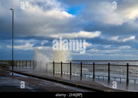 Le onde si infrangono contro una passeggiata Foto Stock