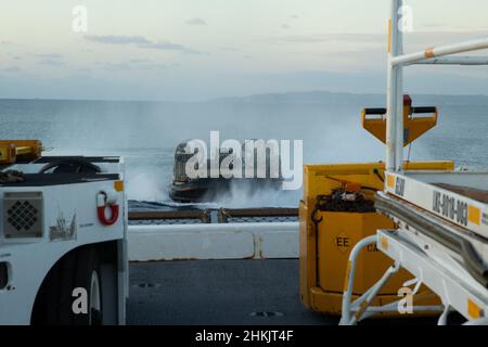 Un atterraggio della Marina degli Stati Uniti, Craft Air Cushion, vola sulla USS Green Bay, base navale White Beach, Okinawa, Giappone, 21 gennaio 2022. L'unità Marine Expeditionary 31st opera a bordo delle navi dello Squadrone anfibio 11 nell'area operativa della flotta 7th per migliorare l'interoperabilità con alleati e partner e servire come risposta pronta a difendere la pace e la stabilità nella regione IndoPacifico. (STATI UNITI Foto del corpo marino di Lance CPL. Yvonne Iwae) Foto Stock