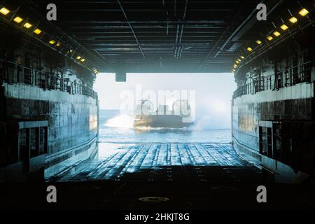 Un cuscino d'aria della Marina degli Stati Uniti (LCAC), vola sulla USS Green Bay (LPD 20), base navale White Beach, Okinawa, Giappone, 21 gennaio 2022. L'unità Marine Expeditionary 31st opera a bordo delle navi dello Squadrone anfibio 11 nell'area operativa della flotta 7th per migliorare l'interoperabilità con alleati e partner e servire come risposta pronta a difendere la pace e la stabilità nella regione IndoPacifico. (STATI UNITI Foto del corpo marino di Lance CPL. Yvonne Iwae) Foto Stock