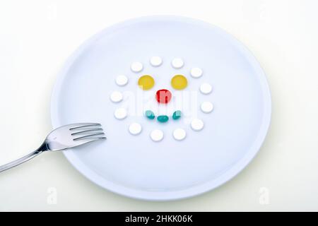 piatto con pillole a forma di viso, immagine simbolica per alimenti sintetici, consumo di compresse, abuso di compresse Foto Stock