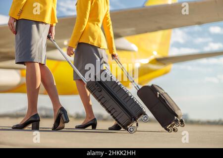 Primo piano di lavoratori di compagnie aeree donne con valigie di viaggio che camminano lungo il campo aereo Foto Stock