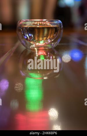 Vetreria per bevande calde su sfondo sfocato, colorata luce al neon. Pulire il teacup. Foto Stock