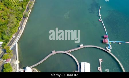 Vista aerea del ponte pedonale sul mare. Stretto ponte di legno con bella marinaio e riflessione. Attrazioni turistiche a Kampung Kerapu Foto Stock