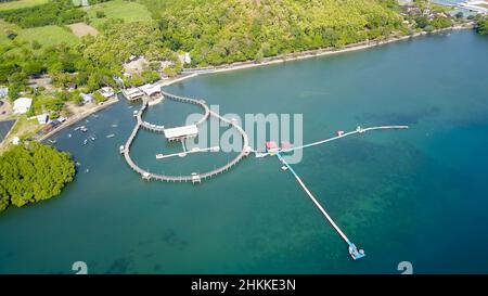 Vista aerea del ponte pedonale sul mare. Stretto ponte di legno con bella marinaio e riflessione. Attrazioni turistiche a Kampung Kerapu Foto Stock