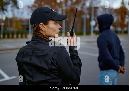Poliziotto donna che utilizza la vista posteriore della radio portatile Foto Stock