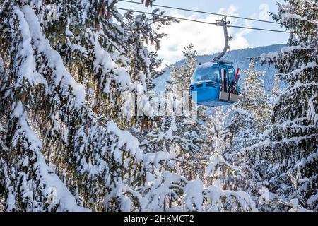 Stazione invernale con cabine di gondola per impianti di risalita e montagne innevate e pini dopo la nevicata, Bansko, Bulgaria Foto Stock