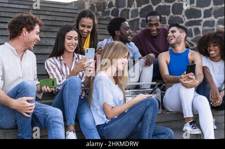 Giovani amici multirazziali divertirsi con il telefono e ascoltare musica con stereo stereo Boombox outdoor - concetto di stile di vita millenario della gioventù Foto Stock