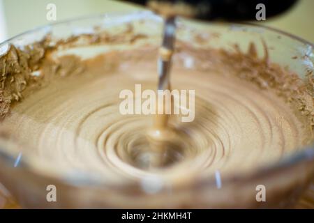 Preparazione del gelato mescolando il cacao in polvere con la panna. Frullare il composto utilizzando il frullatore ruotandolo velocemente in circolare. Foto Stock