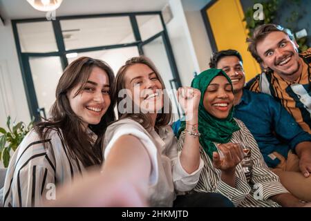 Gruppo di uomini d'affari durante la pausa dal lavoro, scattando foto selfie mentre si gode del tempo libero nella zona relax alla moderna startup open plan Foto Stock