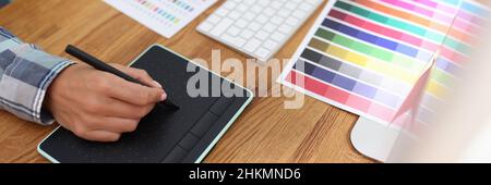 Graphic designer lavora su computer e seleziona schemi di colori Foto Stock