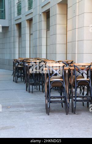 Posti a sedere all'aperto gratuiti nella caffetteria estiva chiusa. Struttura chiusa e tavoli vuoti Foto Stock