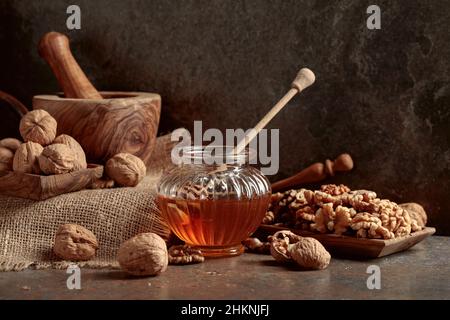 Miele e noci su un vecchio tavolo da cucina. Foto Stock