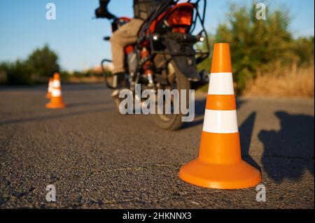 Studente in moto, serpente a cavallo tra coni Foto Stock