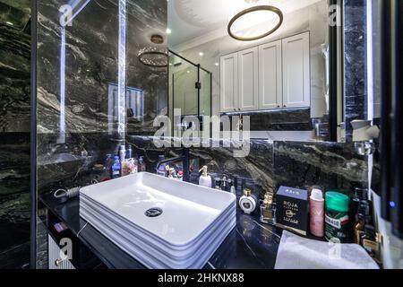 Bagno e wc in elegante versione in bianco e nero. Pavimenti con motivi in marmo bianco e nero. Lavandino con specchio, wc e doccia. Foto Stock