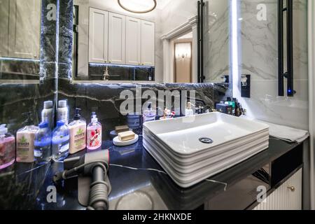 Bagno e wc in elegante versione in bianco e nero. Pavimenti con motivi in marmo bianco e nero. Lavandino con specchio, wc e doccia. Foto Stock