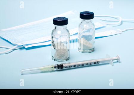 Vaccino del coronavirus, maschere mediche protettive, termometro per il corpo su sfondo medico blu. Foto Stock