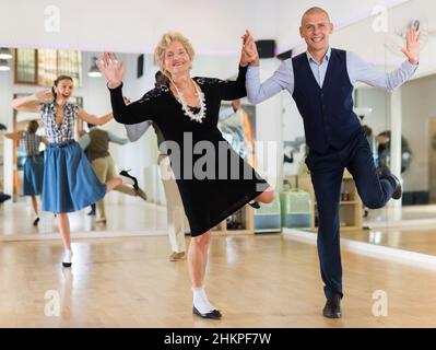 Donna matura imparando a ballare lindy hop con l'uomo più giovane Foto Stock