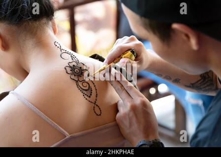 SABAH, MALESIA - 30 MAGGIO, 2019: L'artista henné femminile applica un disegno henné sul womanback in Kota Kinabalu, Sabah Malesia. Foto Stock