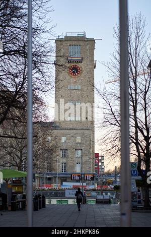 Stoccarda, Germania - 31 dicembre 2021: Edificio della stazione principale di Stoccarda. Edificio dall'esterno con orologio sulla torre. Prima mattina persona in Foto Stock