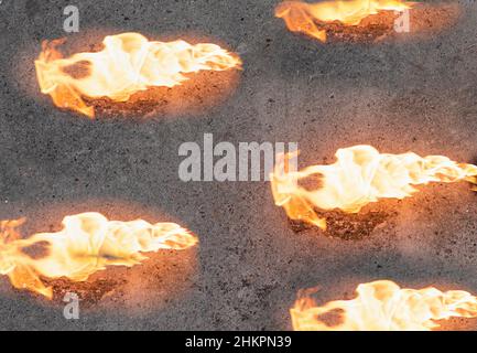 Lingue di fiamme arancioni su sfondo di cemento grigio Foto Stock