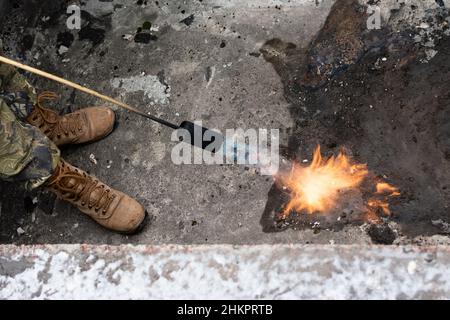 Riparazione del tubo discendente. Riscaldamento della zona del gocciolatoio con un bruciatore a gas durante la riparazione del tubo discendente Foto Stock