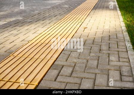 Pavimentazione tattile su passerella pedonale, piastrelle tattili gialle all'aperto. Indicatori tattili della superficie del terreno per non vedenti e ipovedenti, avviso rilevabile Foto Stock