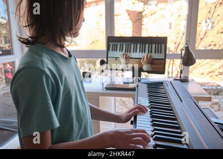 Giovane ragazzo che ha una lezione di pianoforte online. Educazione domestica. Foto Stock