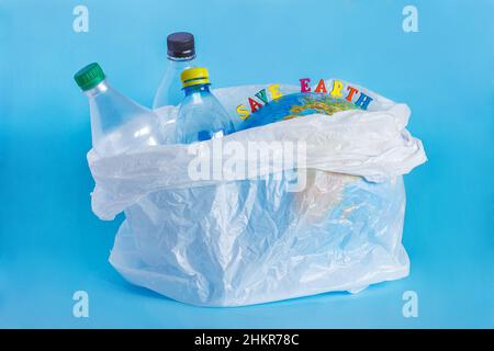 Iscrizione SAVE EARTH, bottiglie di plastica, terra astratta in sacchetto di polietilene, sfondo blu. Concetto problema di ecologia del piano di inquinamento ambientale Foto Stock