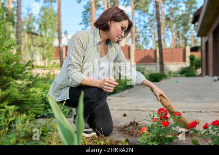 Donna che spazzava con una scopa nel cortile Foto Stock