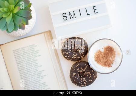 Vista ad angolo alto di una scrivania con caffè e ciambelle Foto Stock
