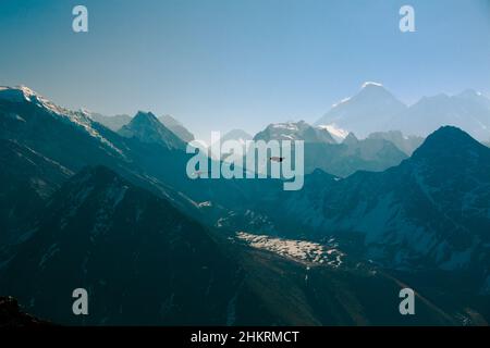 In testa: Due corvi neri che volano sulla valle nella regione di Khumbu del Nepal verso il Monte Everest - visto qui con la nube spiritosa intorno alla sua cima alta Foto Stock