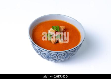 Ciotola di gazpacho, zuppa fredda tipica dell'Andalusia a base di pomodoro, aglio, pepe e cipolla, su sfondo bianco. Foto Stock