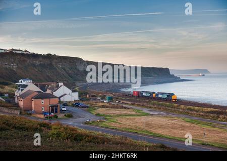 2 servizi ferroviari diretti classe 37 locomotive 37259 + 37611 passando per Parton sulla scenografica linea costiera della Cumbria con un contenitore di rifiuti nucleari di basso livello Foto Stock