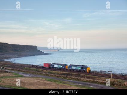 2 servizi ferroviari diretti classe 37 locomotive 37259 + 37611 passando per Parton sulla scenografica linea costiera della Cumbria con un contenitore di rifiuti nucleari di basso livello Foto Stock