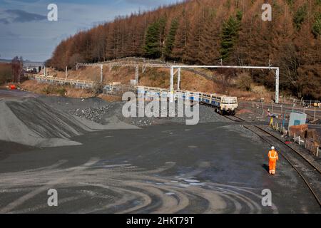 Shunter / tirocinante che guida un treno di carri zavorrati vuoti nel lato di carico alla cava di Shap, Cumbria Foto Stock