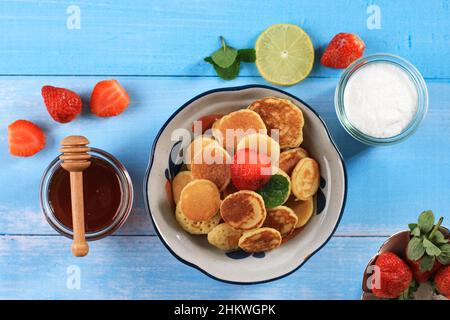 Mini pancake con fragole fresche e sciroppo d'acero, su tavola di legno Foto Stock