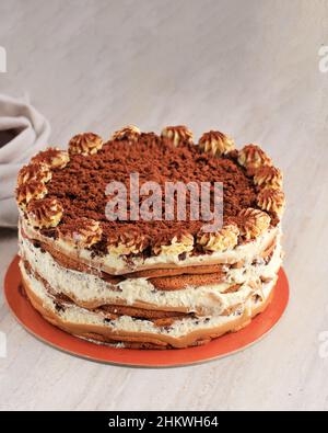 Torta tiramisù rotonda su tavola marrone. Dessert classico italiano con caffè, cacao in polvere, torta Ladyfinger e Mascarpone. Spazio copia per testo Foto Stock
