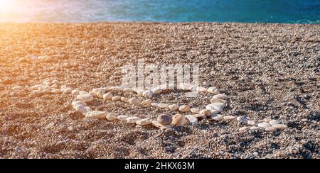 Amore cuore forma su sabbia fatta di ciottoli bianchi, simbolo di amore sulla spiaggia con sfondo mare. San Valentino amore simbolo di forma del cuore, amore Foto Stock