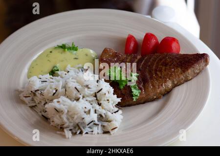 Fettina fritta di filetto di tonno con riso guarnito con salsa sul piatto Foto Stock