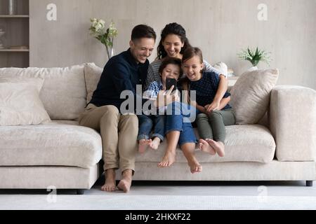 Genitori e bambini felici di divertirsi con lo smartphone a casa Foto Stock