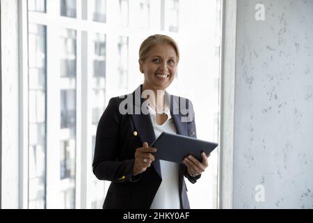 Felice donna d'affari di mezza età di successo con tablet Foto Stock