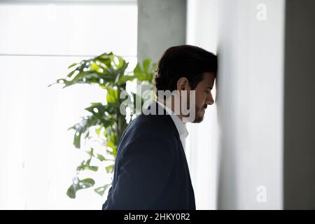 Frustrato uomo d'affari disperato che si appoggia testa sul muro Foto Stock