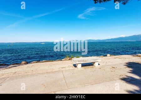 Lago di Garda. Zona pedonale con panca in pietra e panorama del lago vicino alla cittadina di Lazise, località turistica in provincia di Verona. Foto Stock