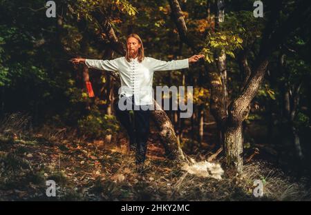 L'uomo caucasico di mezza età pratica tai chi in estate. Meditazione e relax nella natura. Stile di vita sano e sport. Foto Stock