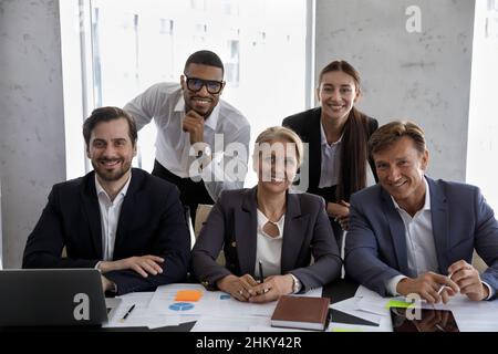 Il team aziendale è felice e si siede al tavolo delle riunioni Foto Stock