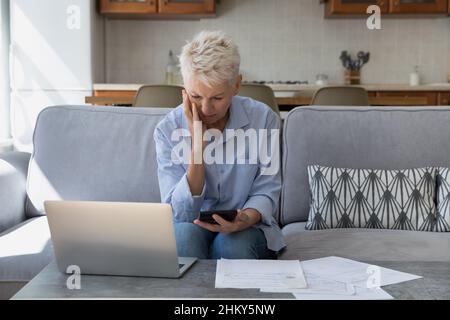 Preoccupata turbata donna di mezza età proprietario di abitazione contando le spese Foto Stock