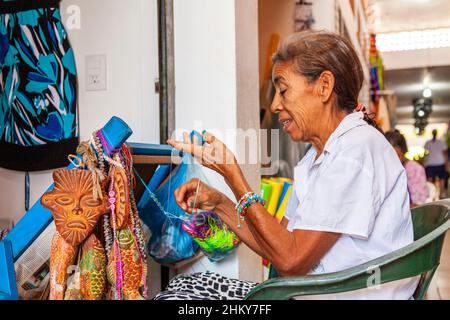 Craftswoman che fa i braccialetti mercato artigianale. Spiaggia di Manzanillo. Oceano Pacifico. Colima. Messico, Nord America Foto Stock