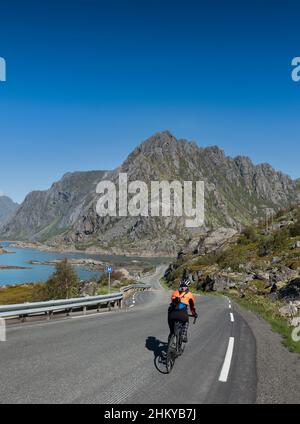 Ciclista femminile sulla strada per Henningsvær, Isole Lofoten, Norvegia. Foto Stock