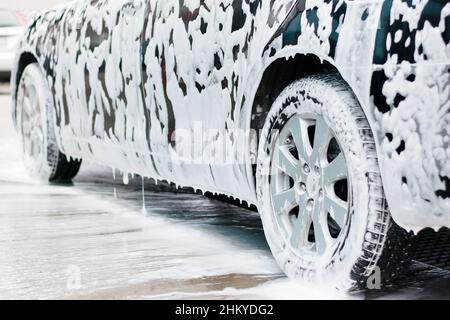 Lavaggio auto, schiuma di pulizia attiva della prima fase defluisce verso  il basso del cofano auto e fari, primo piano Foto stock - Alamy